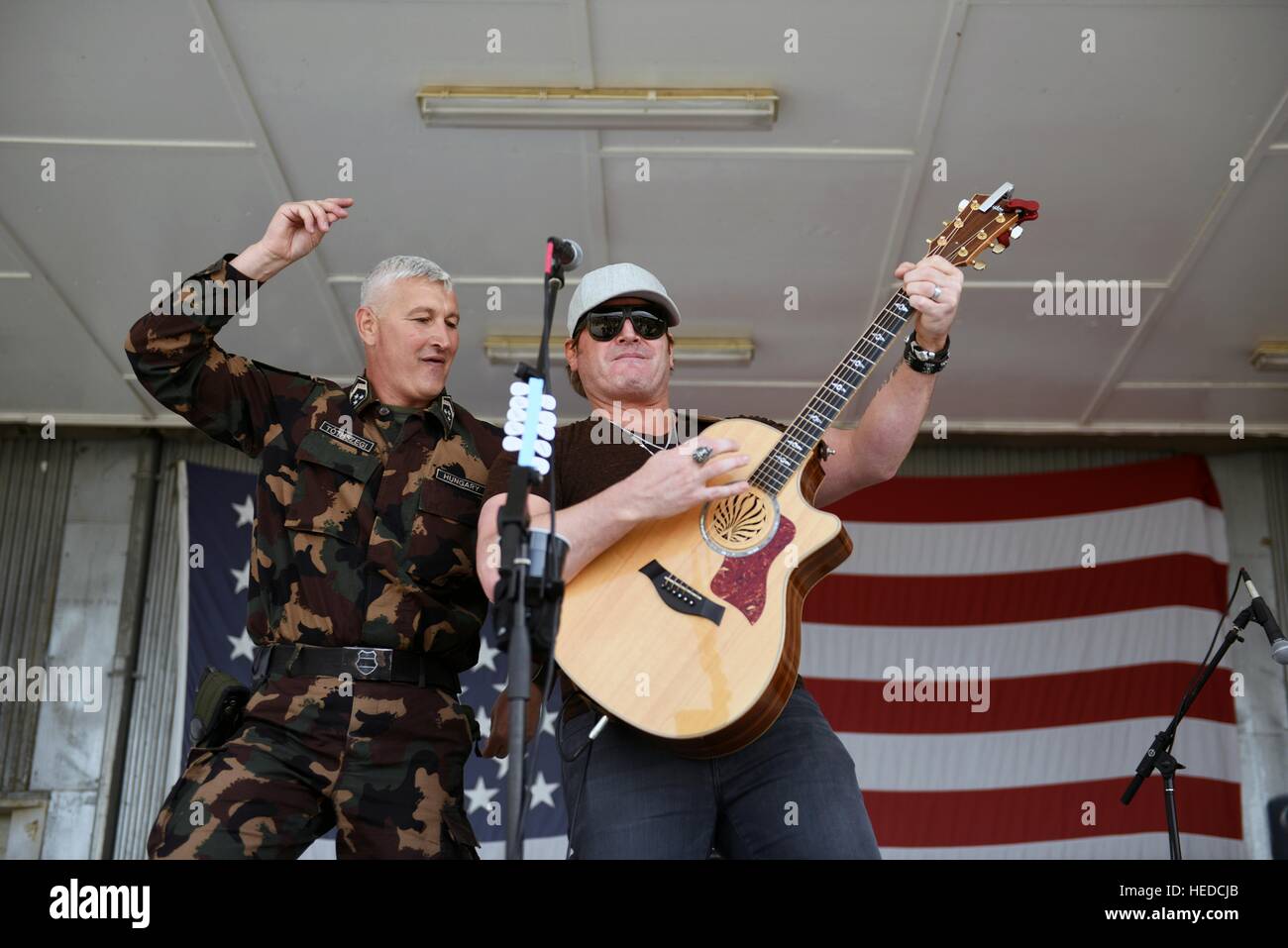 A Hungarian soldier joins in onstage with country music singer Jerrod Niemann as he performs for U.S. troops at a National Guard USO Tour May 18, 2016 in Kuwait. Stock Photo