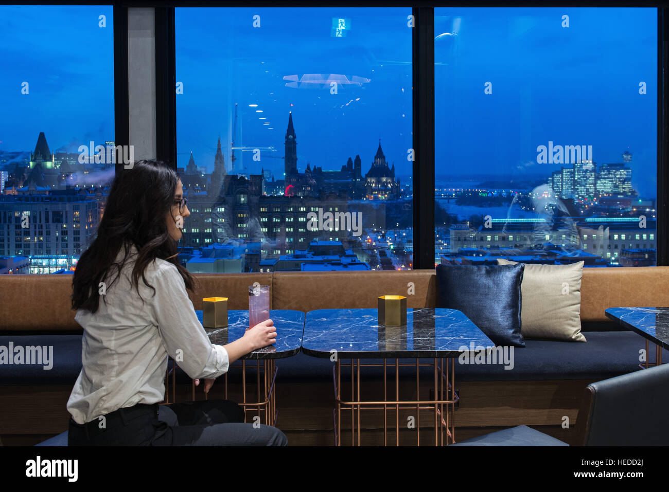 woman enjoying a drink and the view of Ottawa Skyline at dusk from the lounge at the top of Andaz Hotel, 325 Dalhousie, Ottawa Stock Photo