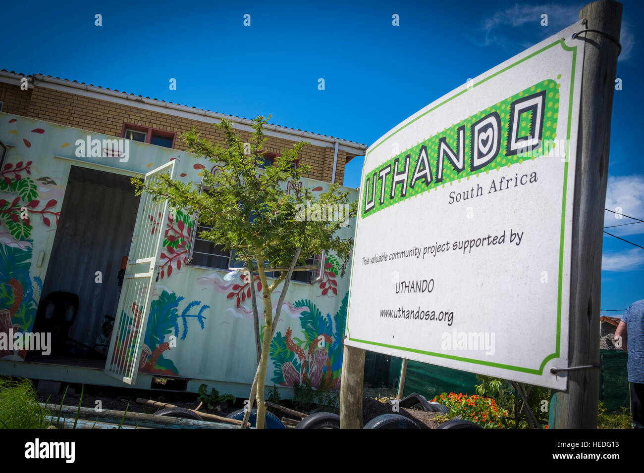 The sign of Uthando, a company that links responsible tourism to community development projects, at the site of one of their projects in Khayelitsha township that encourages school children to get into gardening and educates them about healthy eating Stock Photo