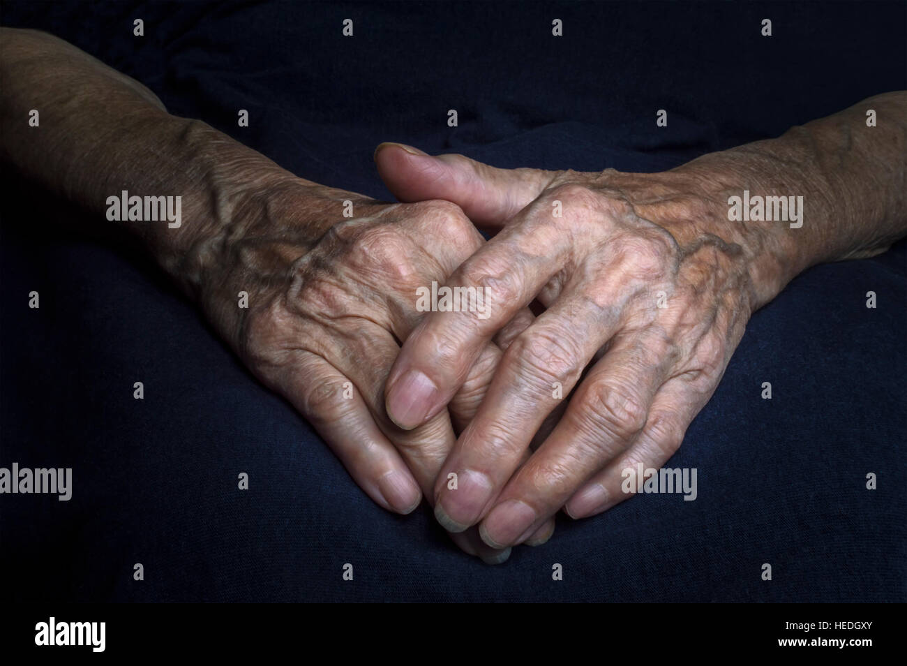 Hands of an old woman with wrinkled and wrinkles on dark background. Stock Photo