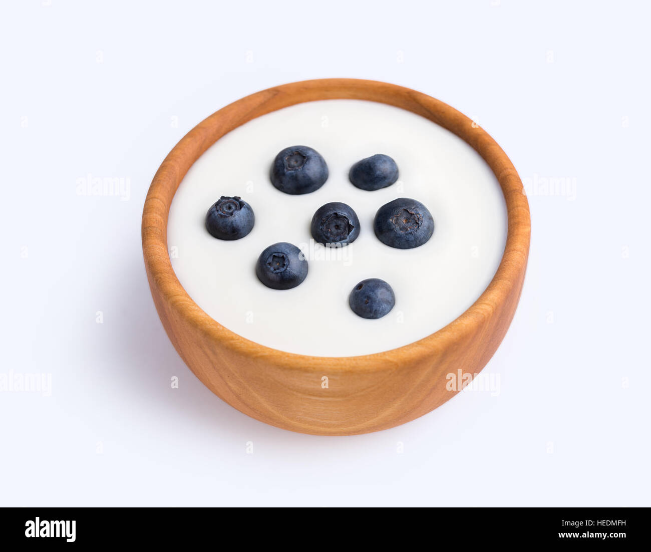 White yogurt in natural wooden bowl with blueberries. Stock Photo