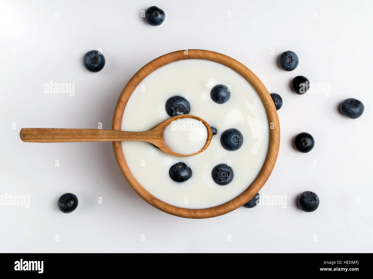White yogurt in natural wooden bowl with blueberries. Top view. Stock Photo