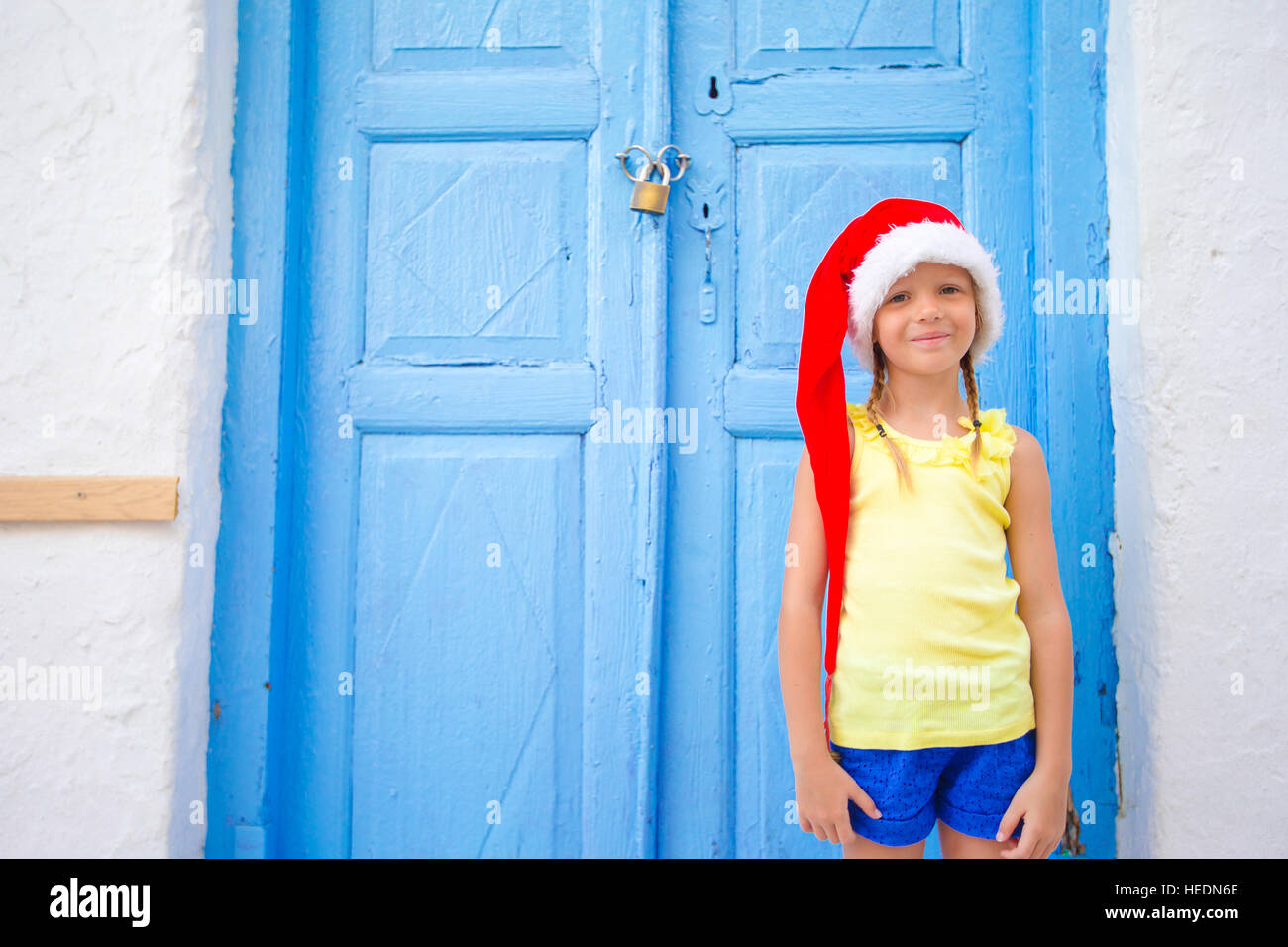 Little girl in santa hat outdoors in old street on Christmas vacation