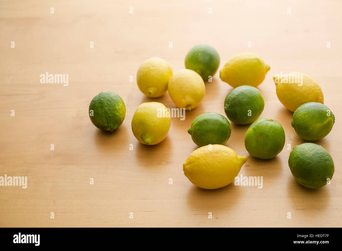 A bunch of a lemons and limes grouped together on a table. Stock Photo