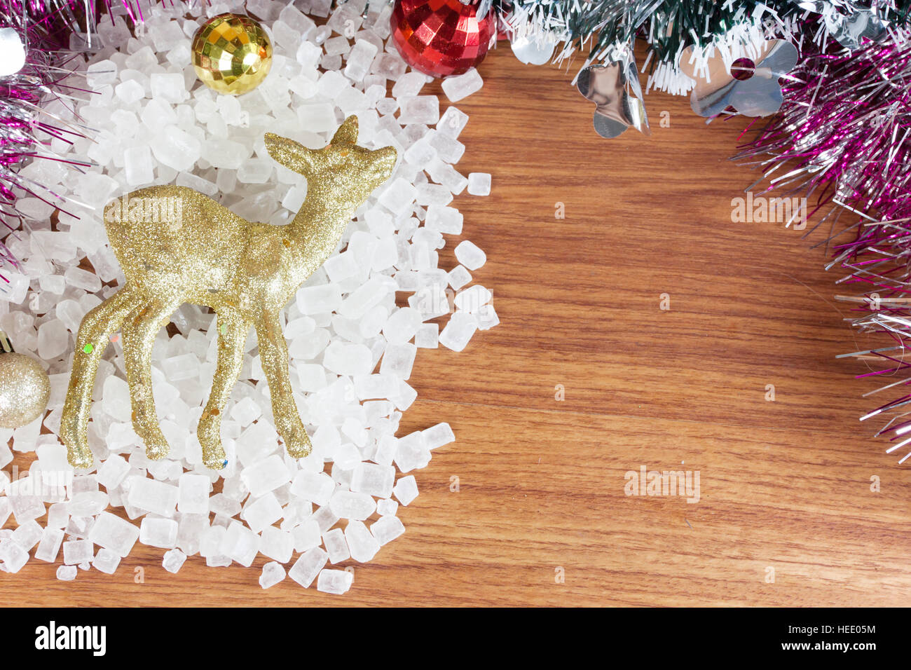 Deer color gold on a pile of white crystalline. Red and yellow Christmas Balls Ornaments on wood, Stock Photo