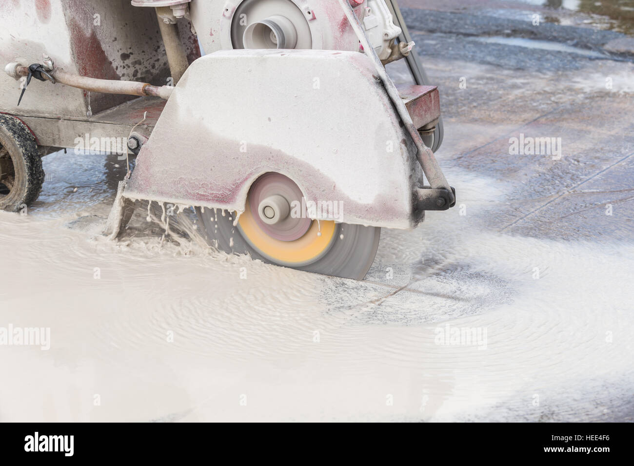 A worker cutting concrete road with diamond saw blade machine Stock Photo
