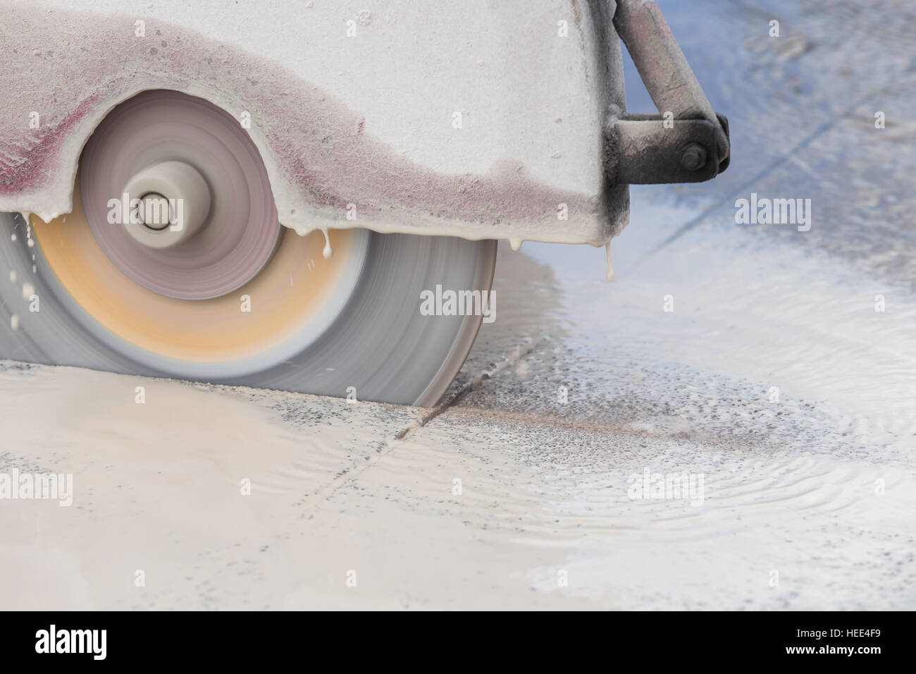 A worker cutting concrete road with diamond saw blade machine Stock Photo