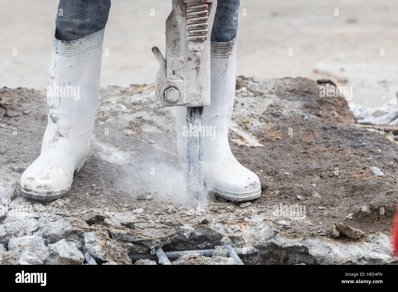 Construction worker removes excess concrete with drilling machine in