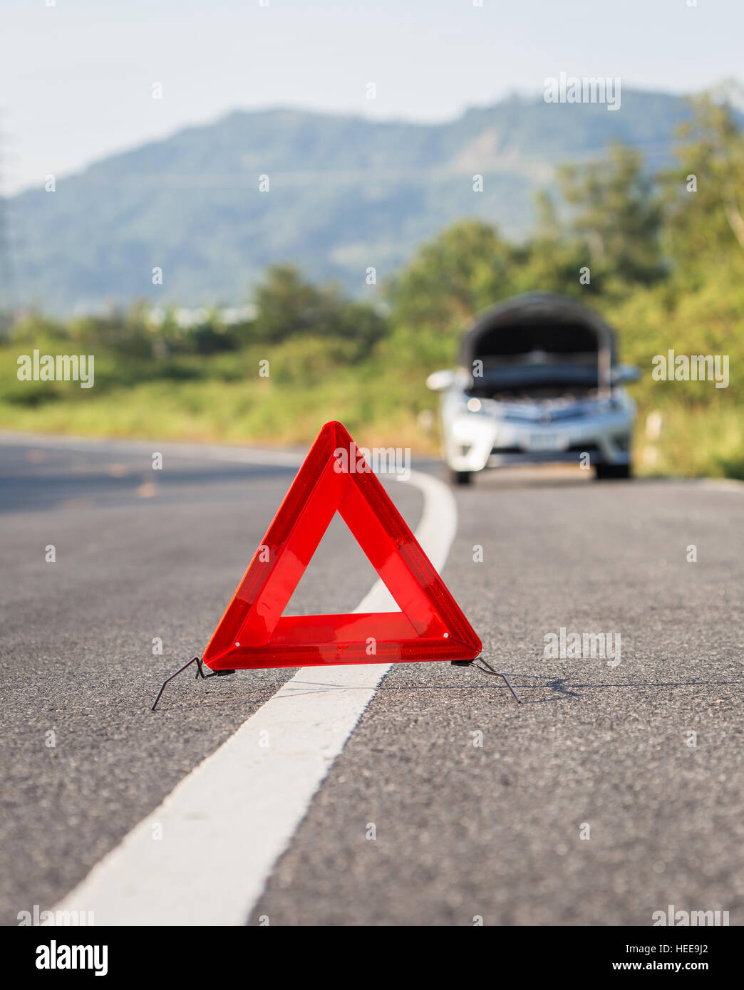 Red emergency stop sign and broken silver car on the road Stock Photo