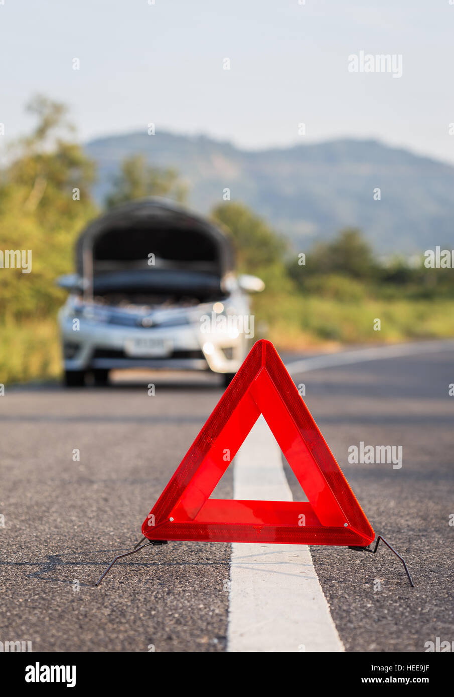 Red emergency stop sign and broken silver car on the road Stock Photo