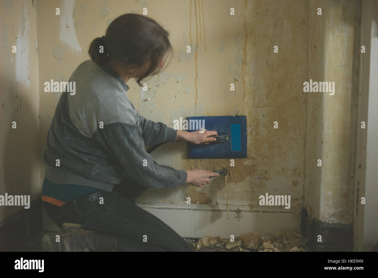 A young woman is removing wallpaper with a steamer stock photo alamy