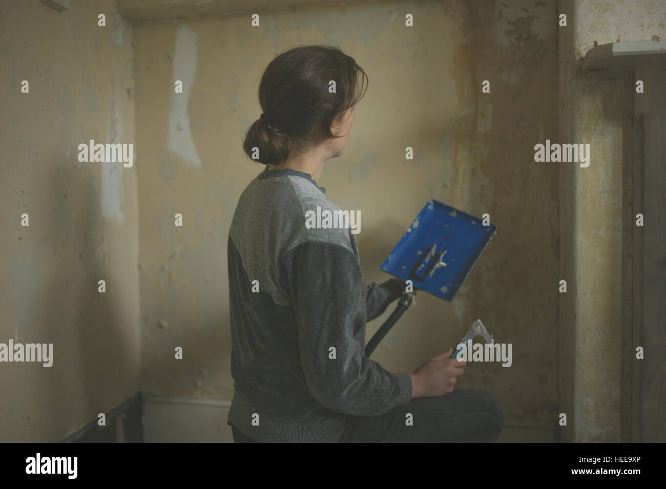 A young woman is removing wallpaper with a steamer stock photo alamy