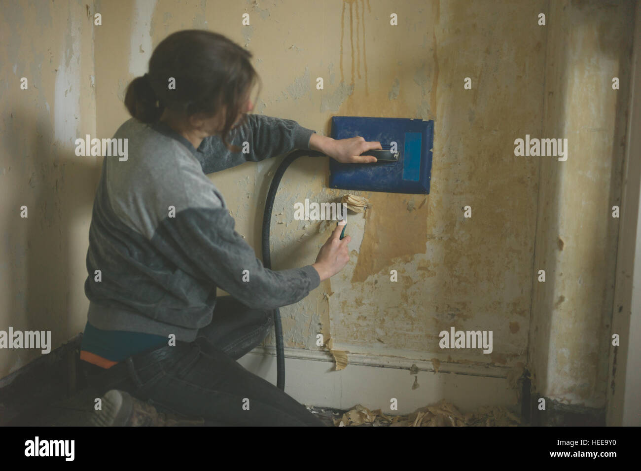 A young woman is removing wallpaper with a steamer stock photo alamy