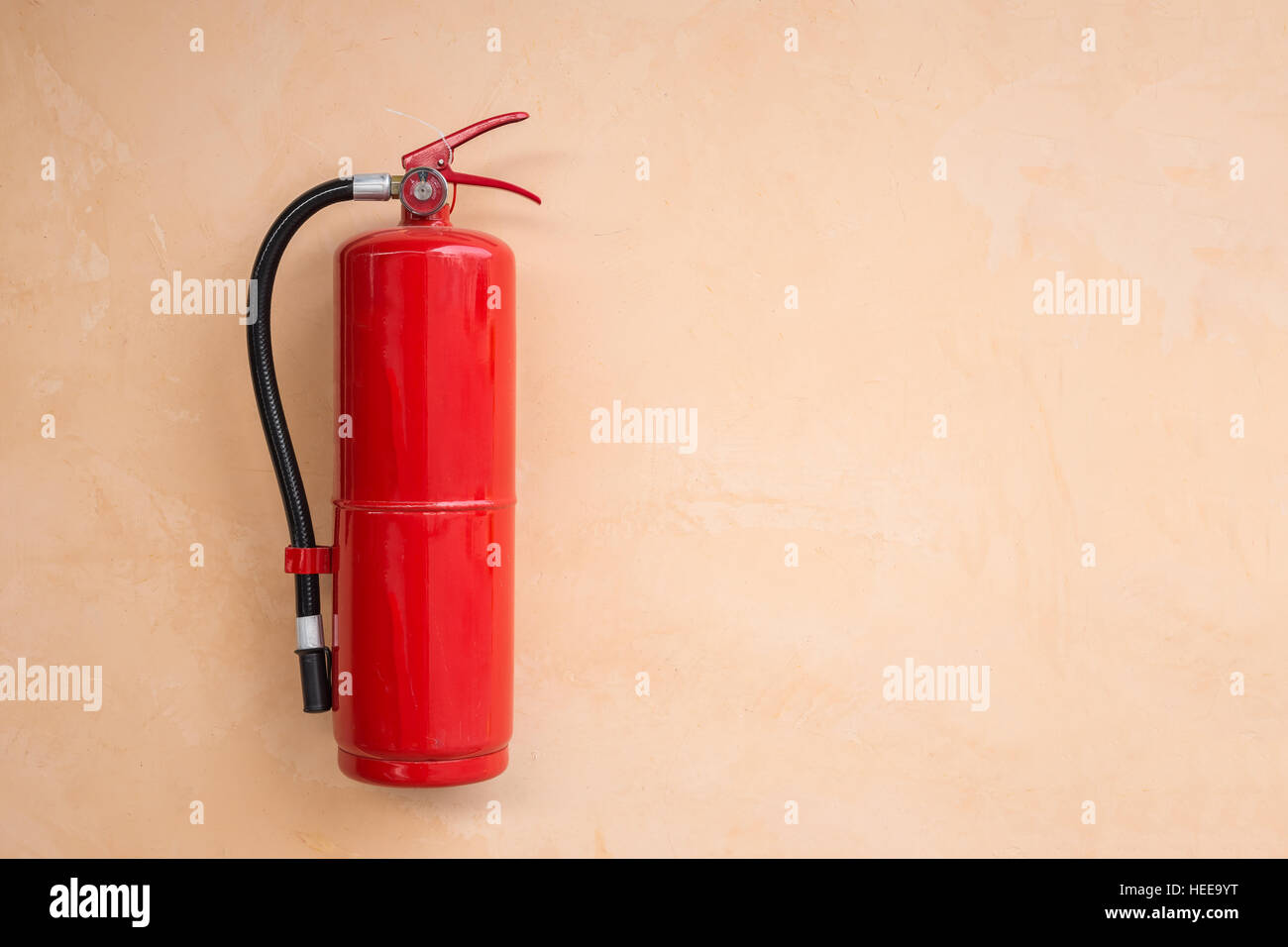 New red fire extinguisher tank on orange wall Stock Photo Alamy