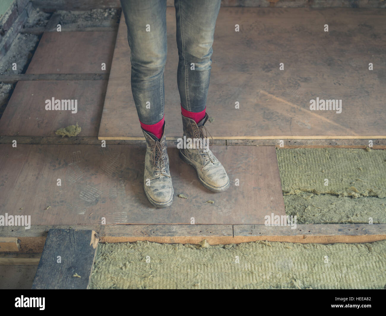 The Feet And Legs Of A Worker Standing On A New Subfloor In A Loft