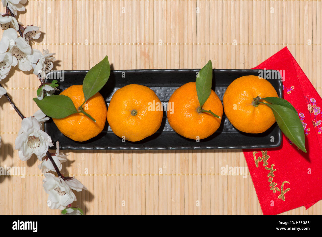 Mandarin oranges and Lunar New Year with text 'Happy New Year' on red pocket. Tet Holiday concept. Stock Photo