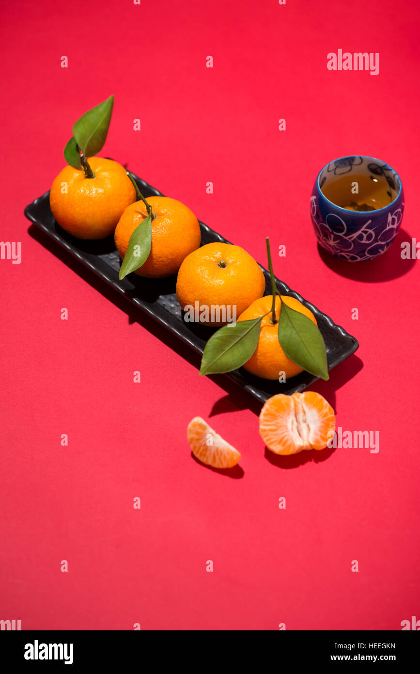 Chinese new year celebration with tangerine and tea on red background Stock Photo