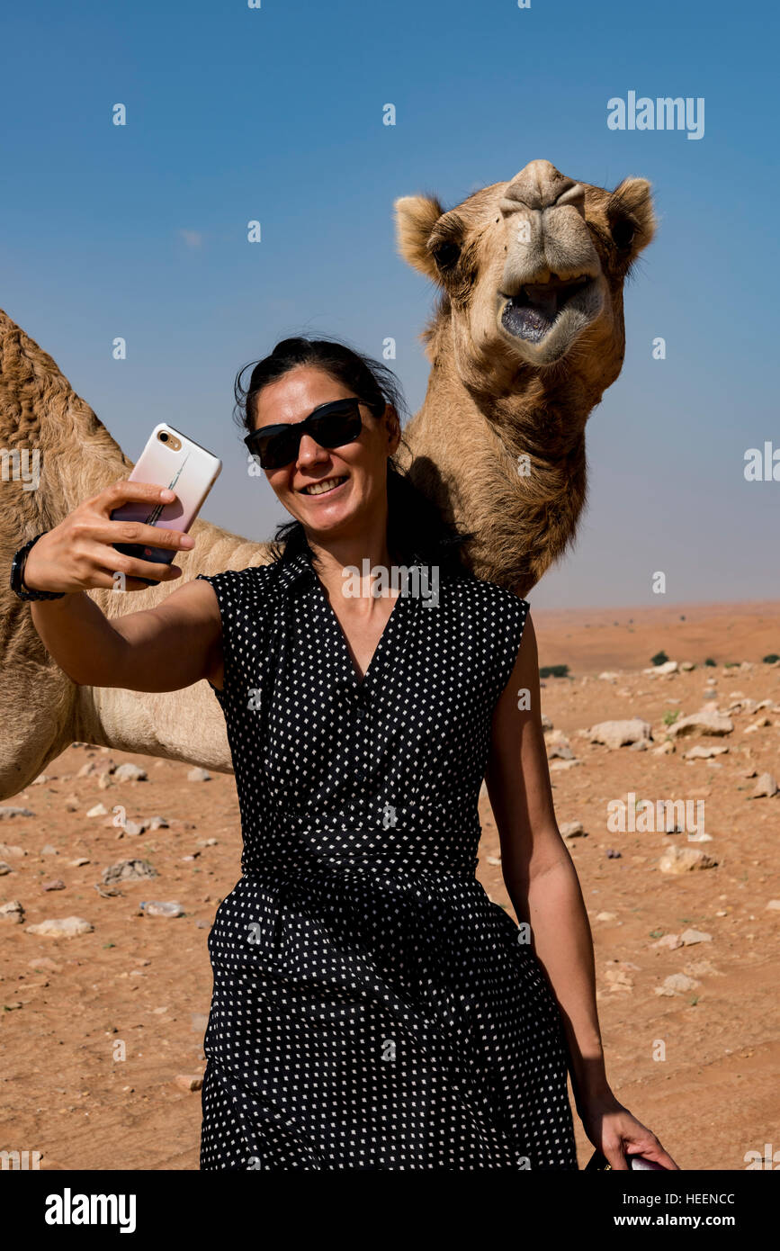 Mature Woman taking a selfie with a camel in the desert Stock Photo