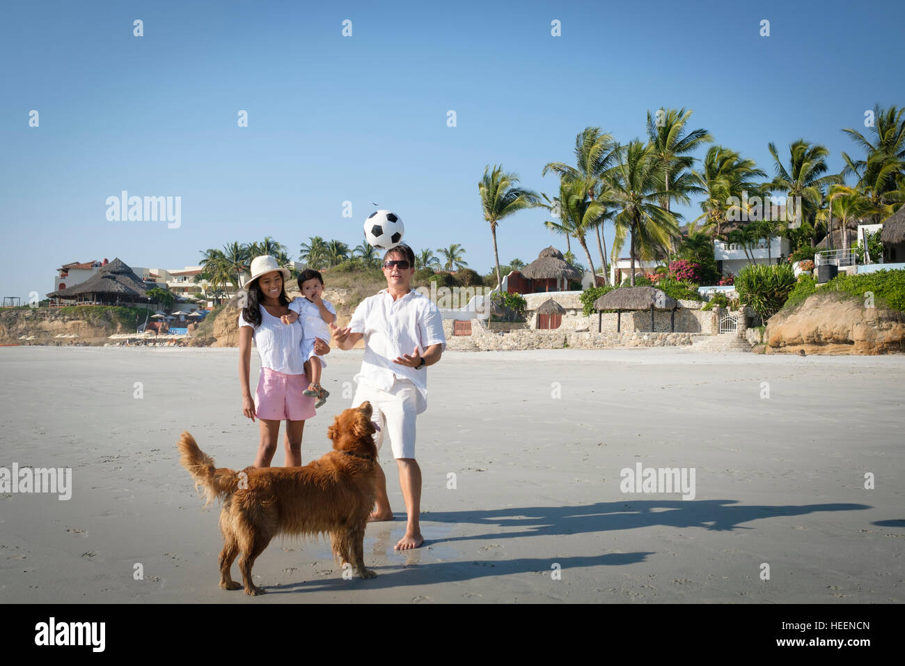 Family with toddler boy and Golden Retriever dog playing ball at the beach. Riviera Nayarit Mexico. Stock Photo