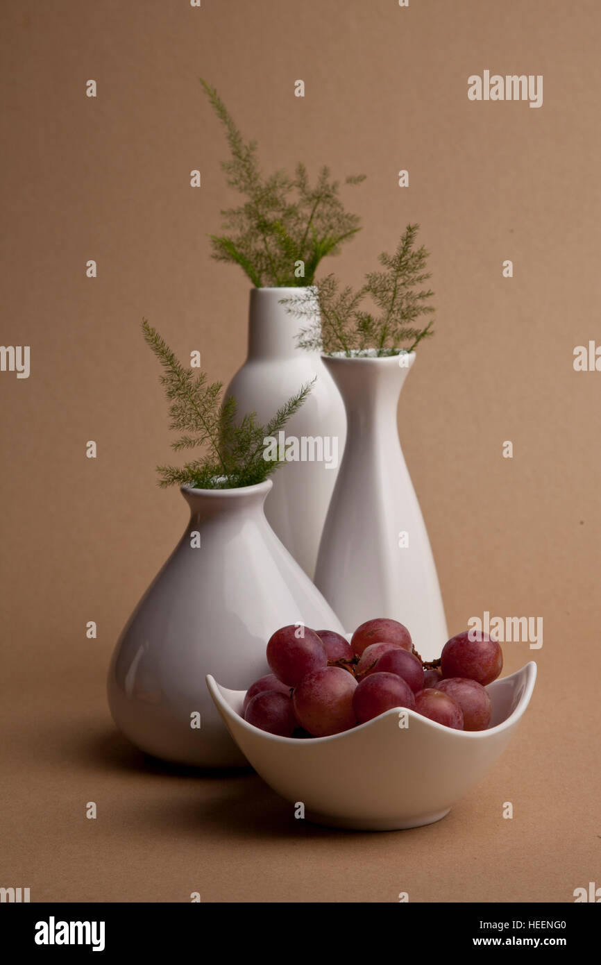 Porcelain vases and a bowl of grapes Stock Photo