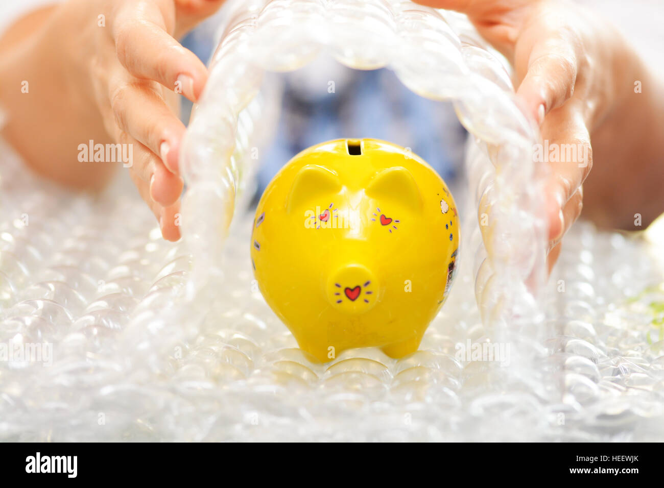 Protect your economies concept with yellow piggy bank covered by bubble wrap Stock Photo