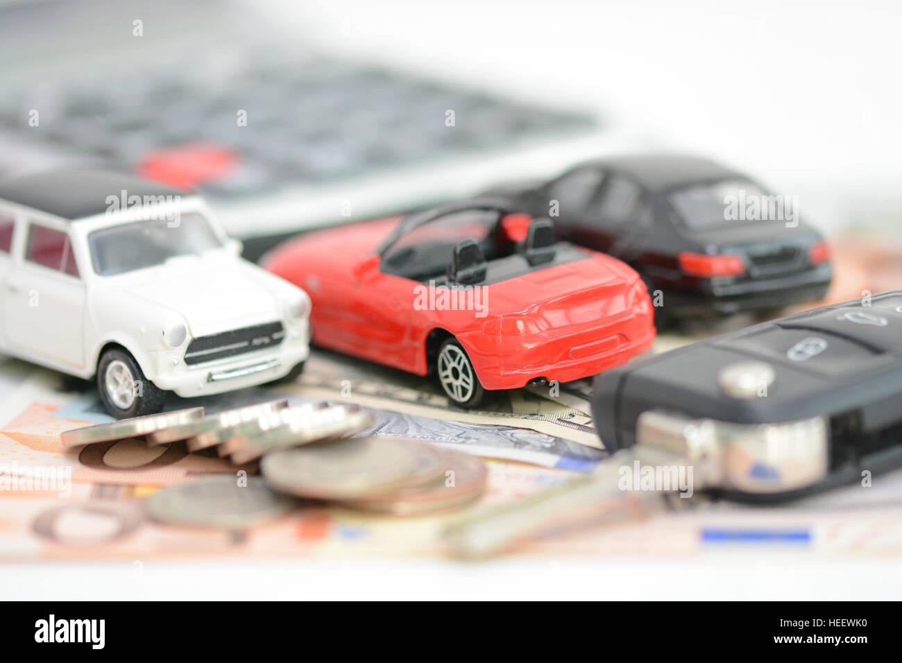 Buying or renting a car concept with car toys, car key, coins and bills Stock Photo