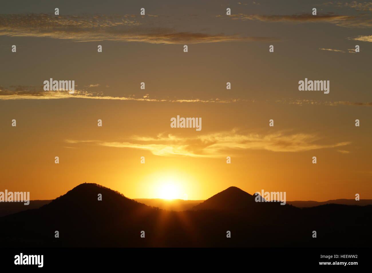 A fiery sunset over the volcanic plug Glasshouse Mountains on the Sunshine Coast of Queensland, Australia. Stock Photo