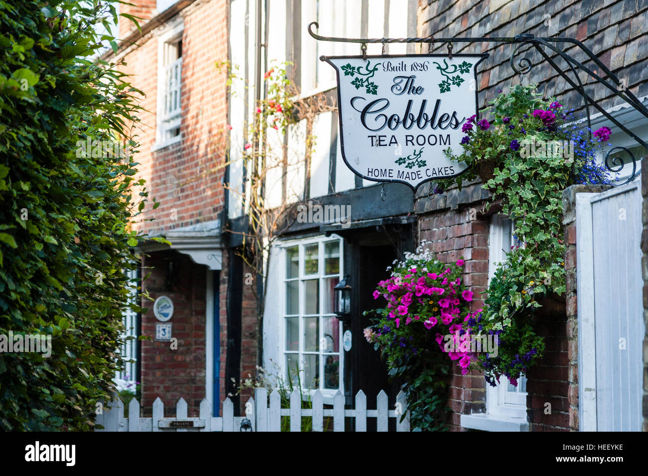England, Rye. View along Terraced row of brick houses built around 1840 with the sign for the 'Cobbles Tea Room'. Sunshine, daytime. Stock Photo