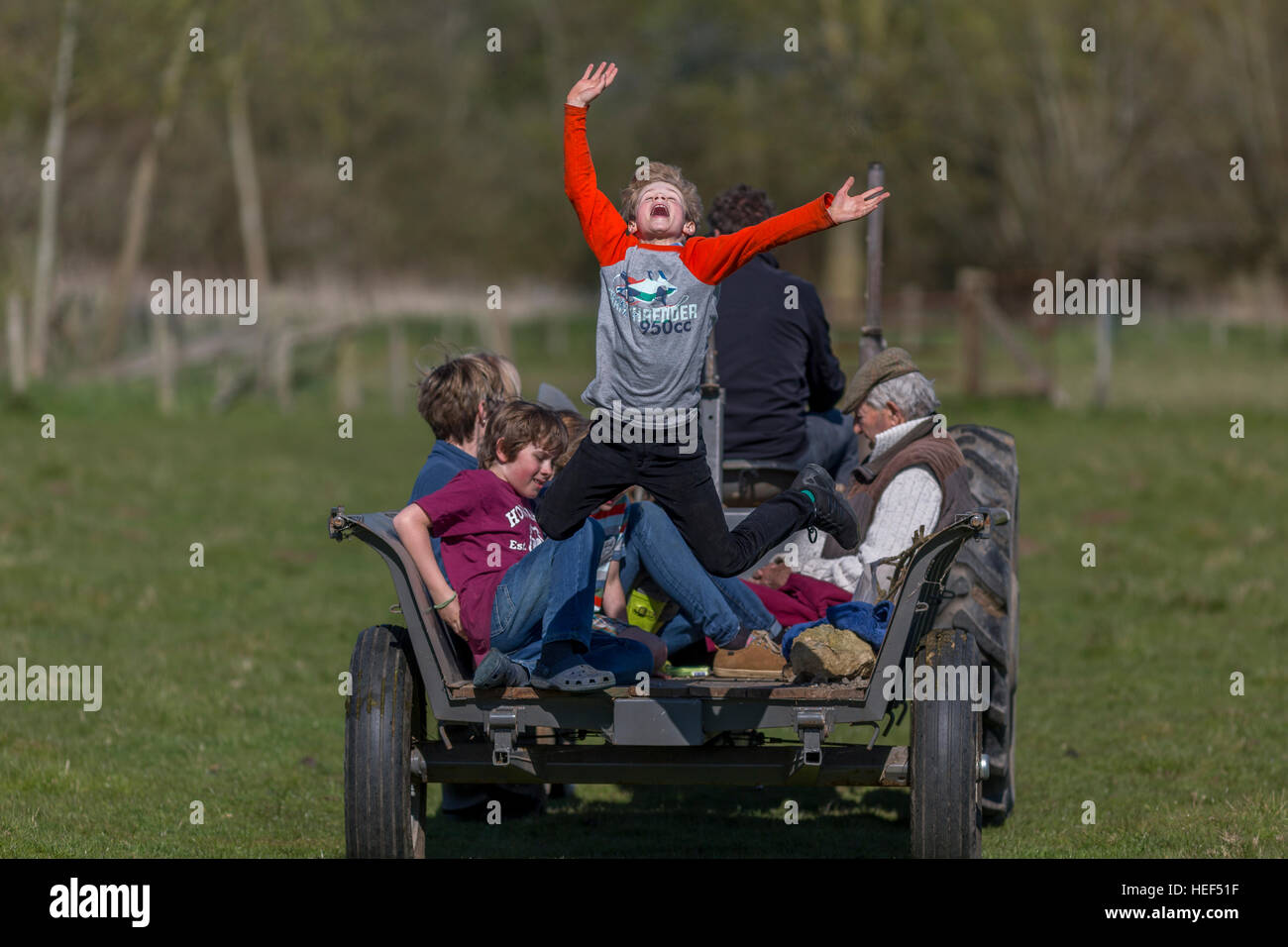 Boy making spectacular jump off the back of a vintage tractor's trailer