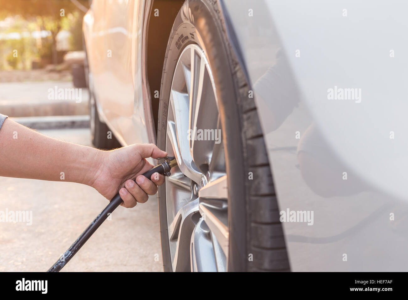 Man checking air pressure and filling air in the tires of his car Stock