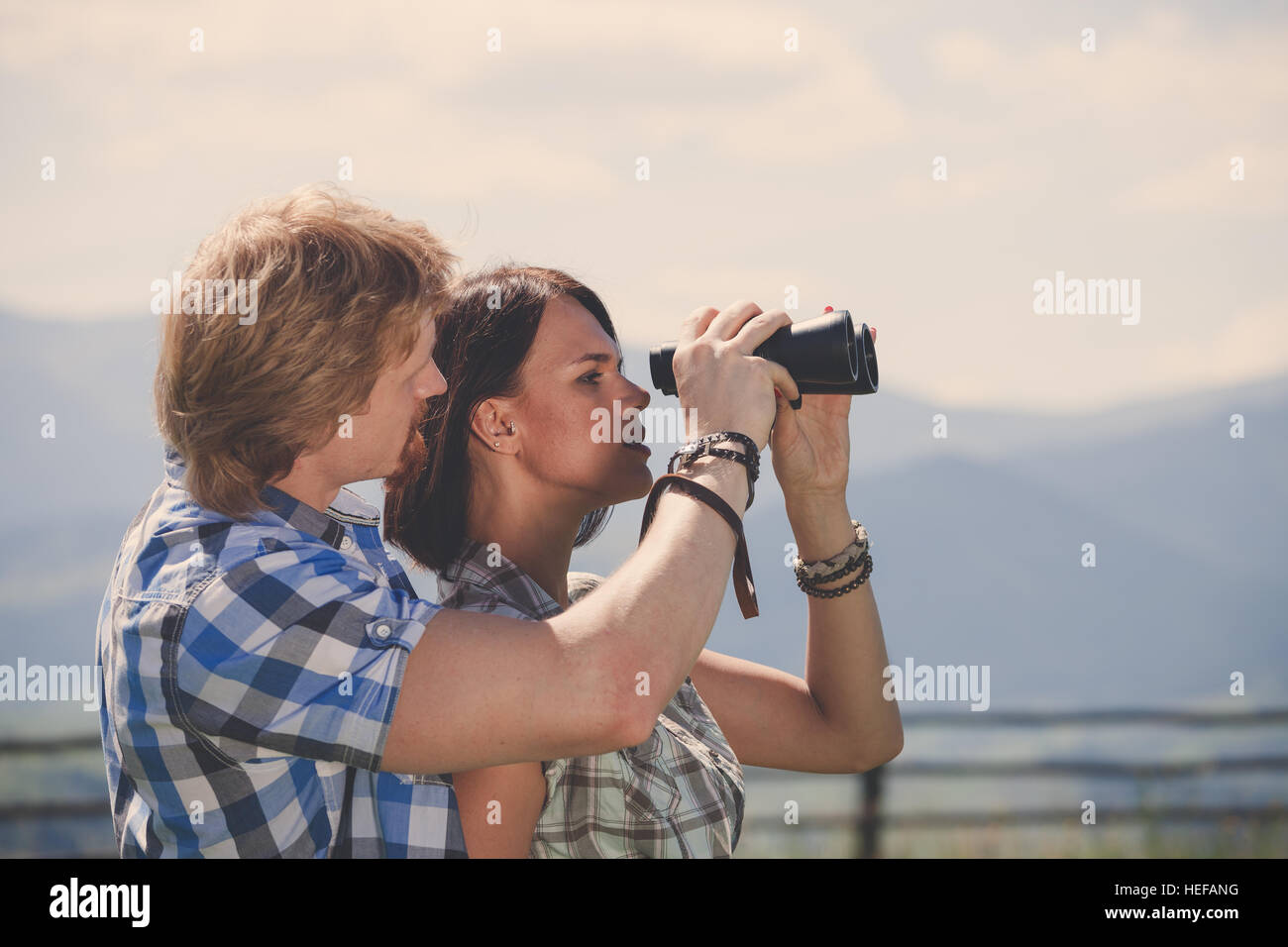 Young couple of travelers looking through binoculars Stock Photo