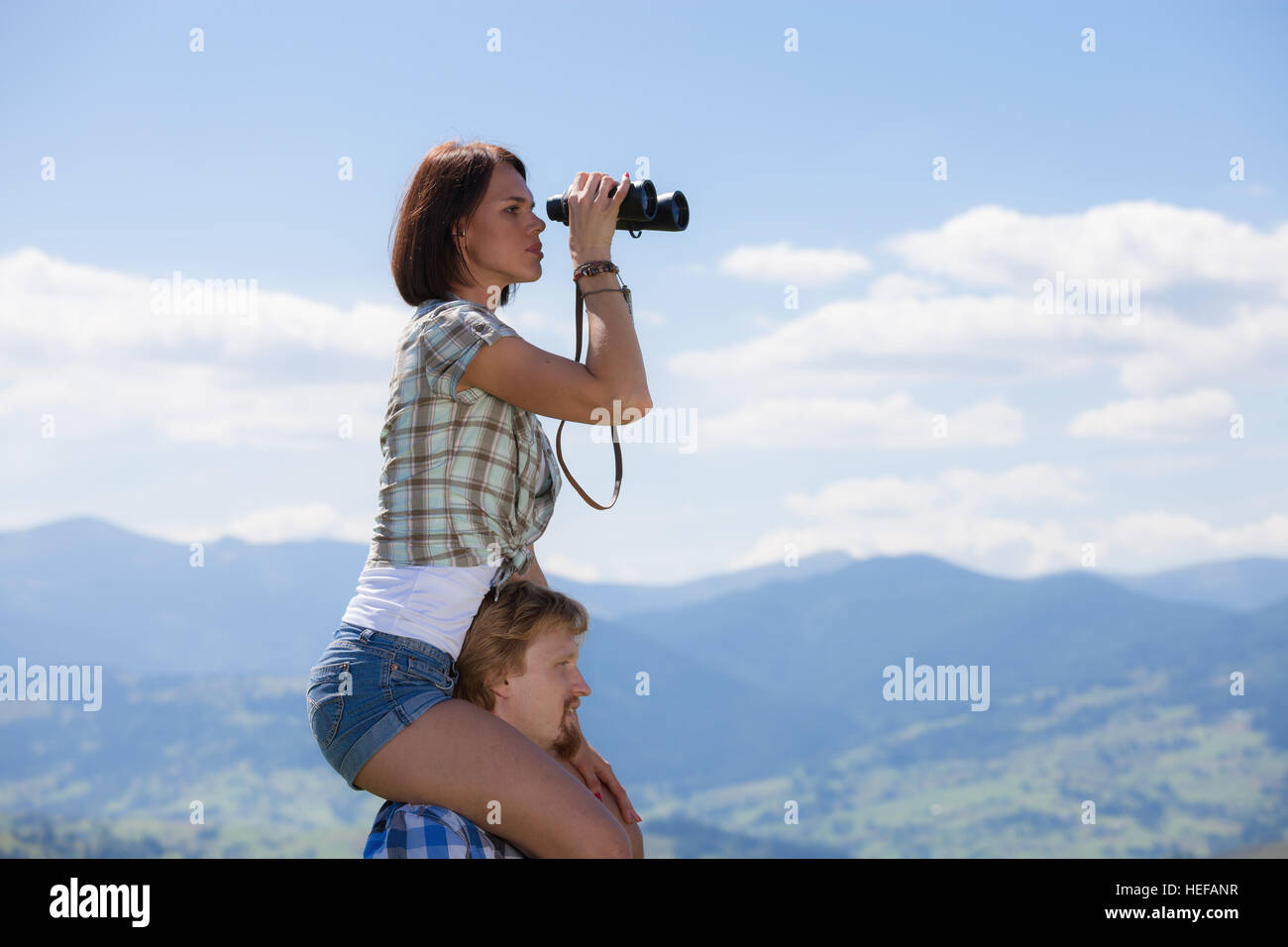 Young couple of travelers looking through binoculars Stock Photo