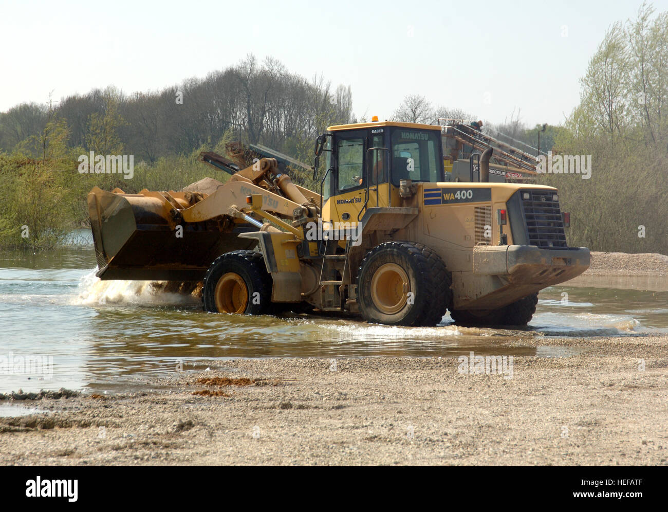 Large front loader digger working in a quarry lake, dumping tons of