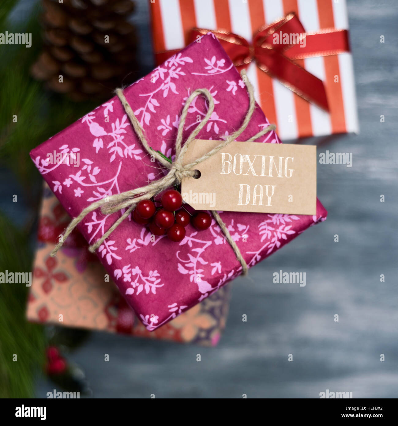 high-angle shot of some cozy gifts wrapped in different nice papers and tied with ribbons and strings of different colors, with a paper tag tied to on Stock Photo
