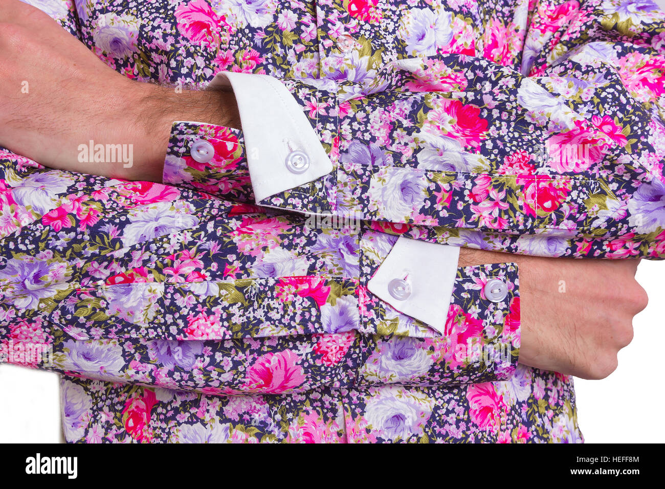 Man dressed in a stylish, floral shirt in purple, black and pink - close-up of crossed arms, folded cuffs and buttons Stock Photo