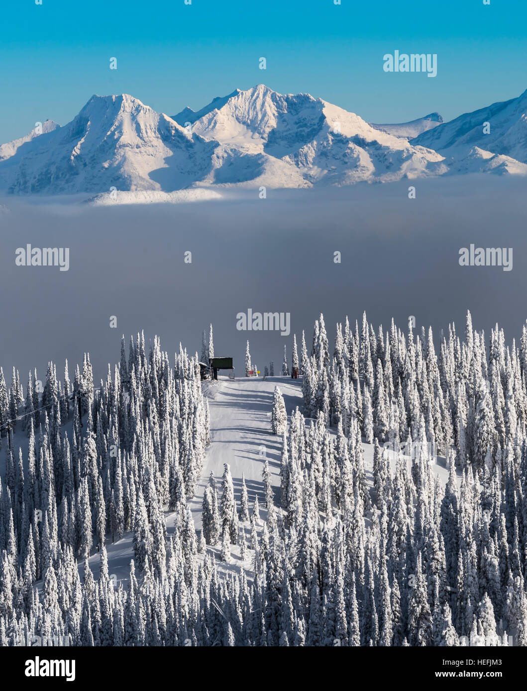 Snow covered mountain top with ski lift at the top of another. Fresh