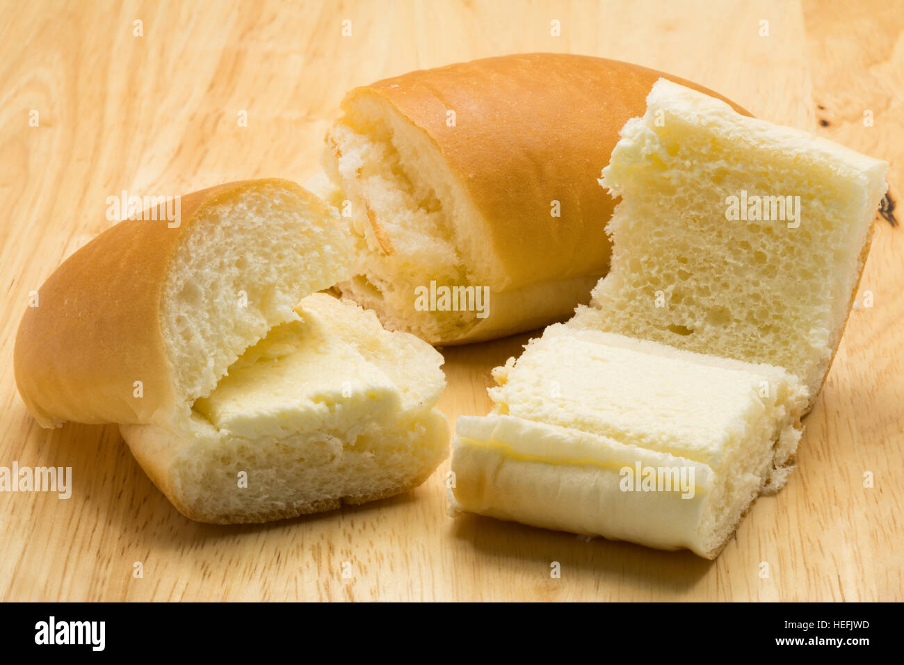 Hotdog bread filled with sweetened butter cream on a wooden board Stock Photo