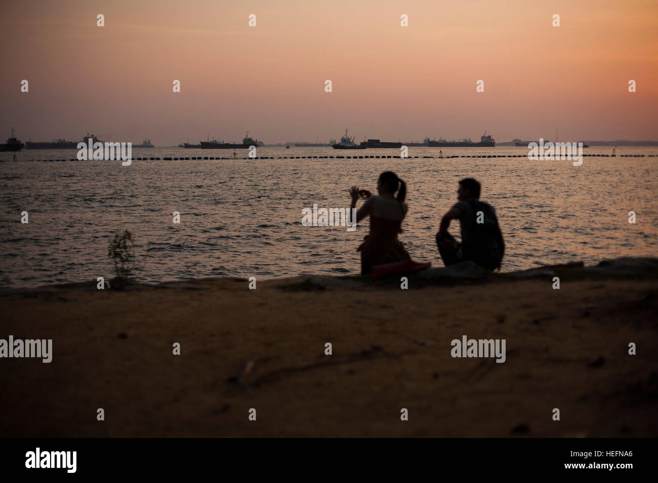 Silhouette of a couple watching colorful sunset on beach Stock Photo ...