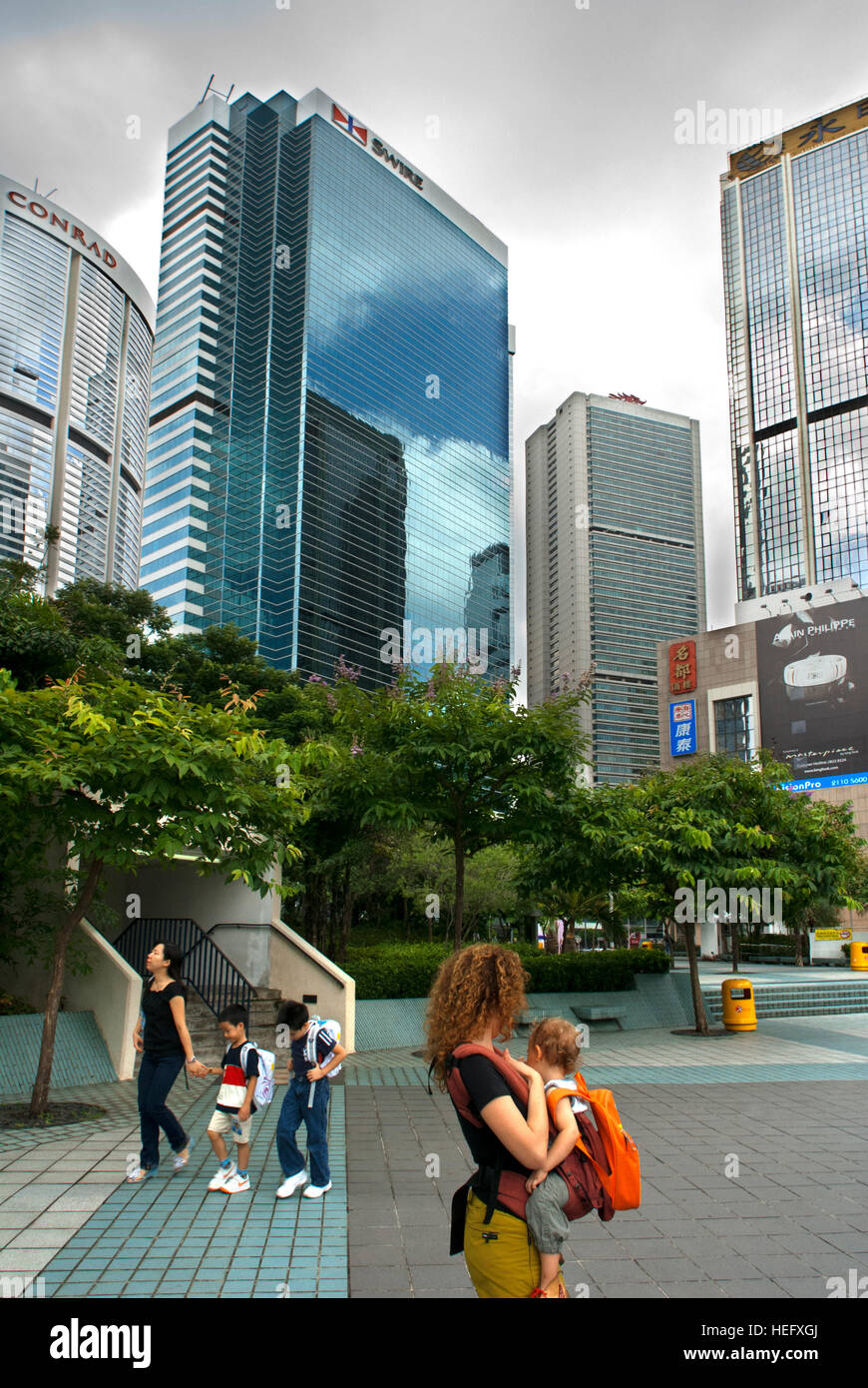 Mother with her child in the Financial centre of Hong Kong with his moderm skyscrapers. Central Business District, Hong Kong, China Stock Photo