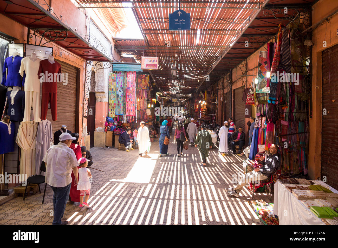 Tourists and locals walking through the souks in the old medina of Marrakesh, Morocco Stock Photo