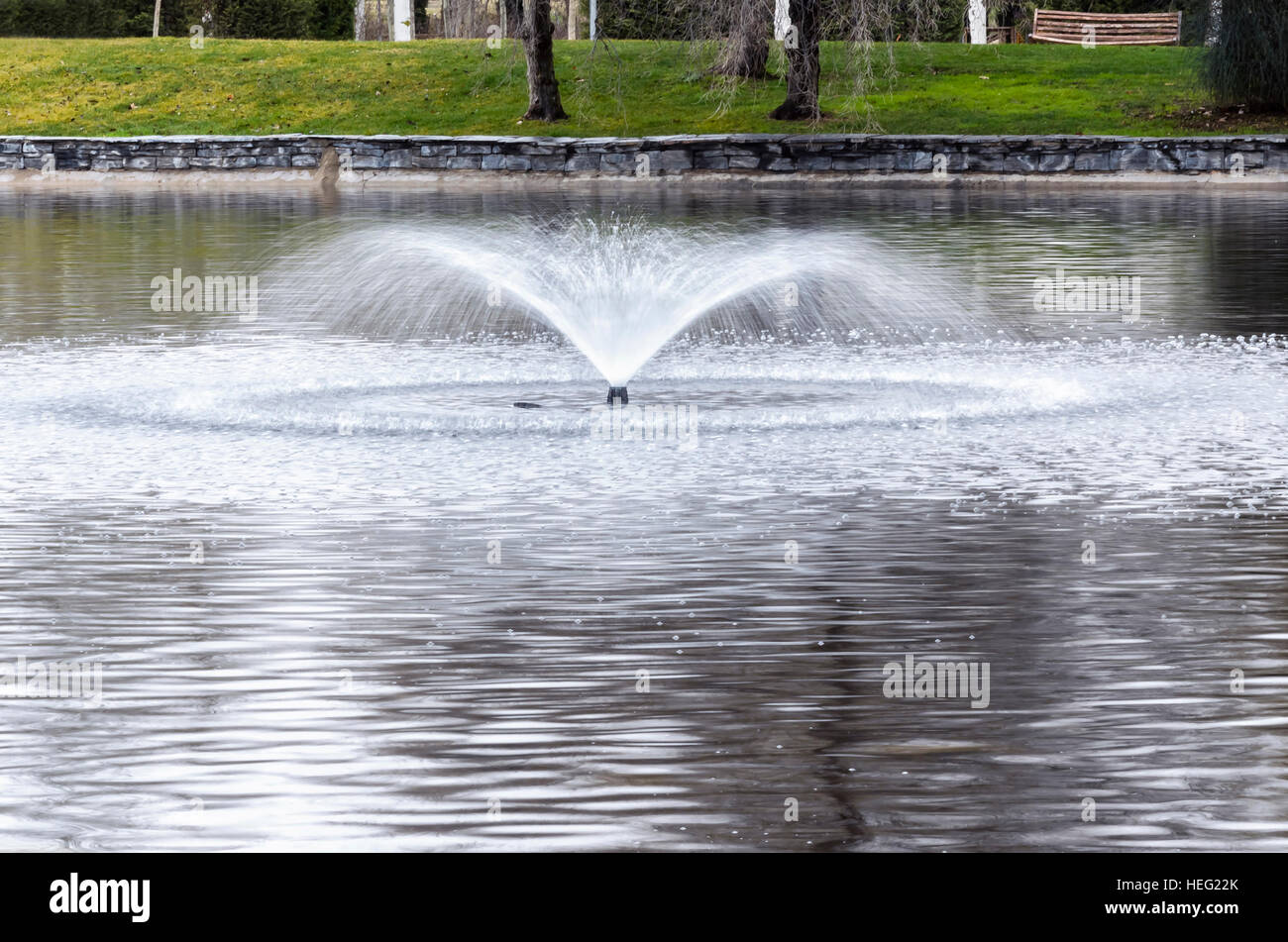 Winter at the urban park. Fountain of pond. Bubbles in the water. Green ...