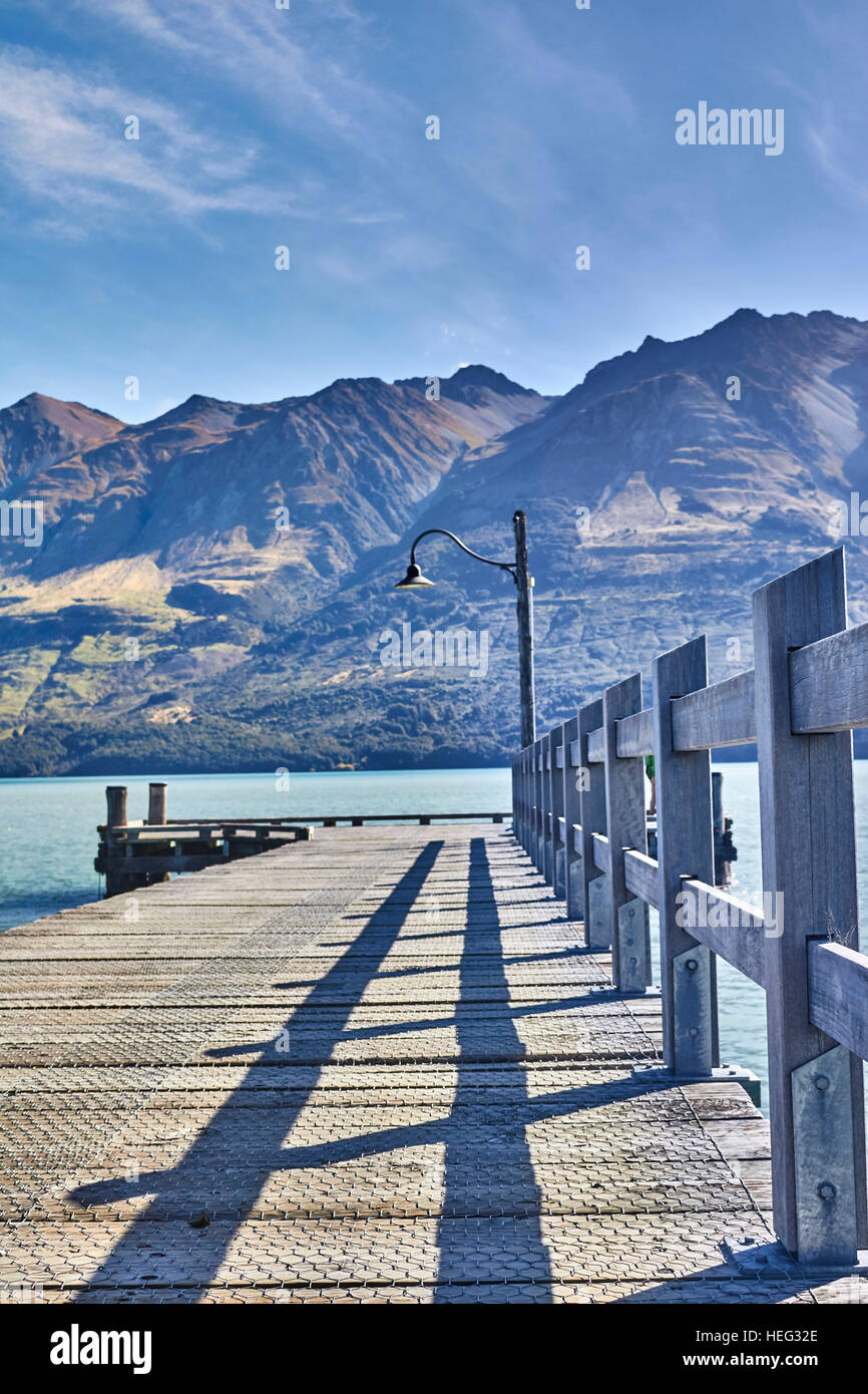 Neuseeland, SÃ¼dinsel, Glenorchy, langer Holzsteg fÃ¼hrt in See, Berge umranden, klares Wasser, malerisch, lange Schatten, alte geschwungene Laterne Stock Photo