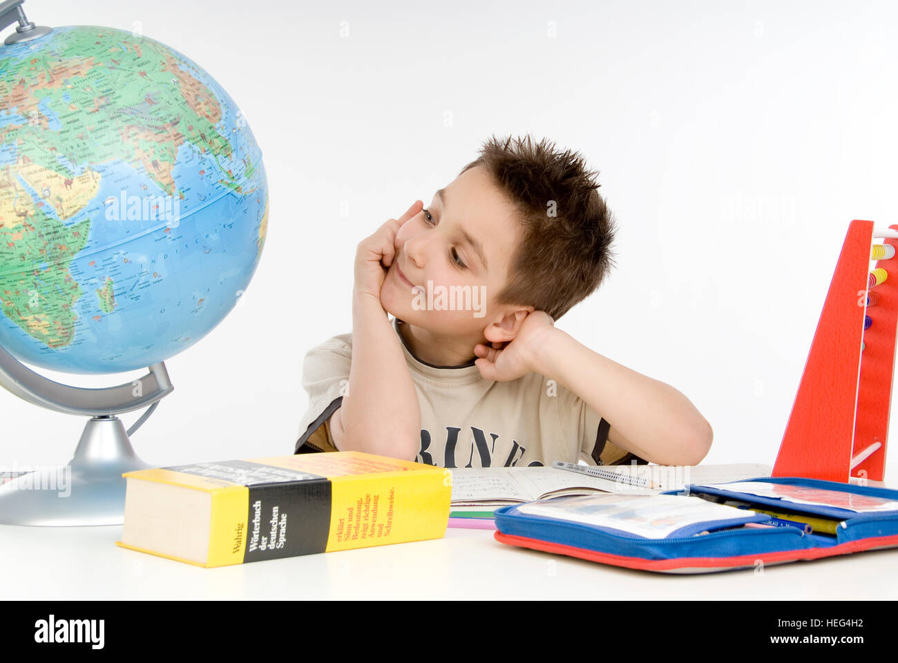 Schoolboy, seven-year-old boy doing his homework, thinking Stock Photo