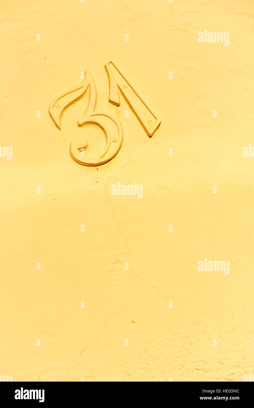 Number 31 on a yellow plaster wall. Stock Photo