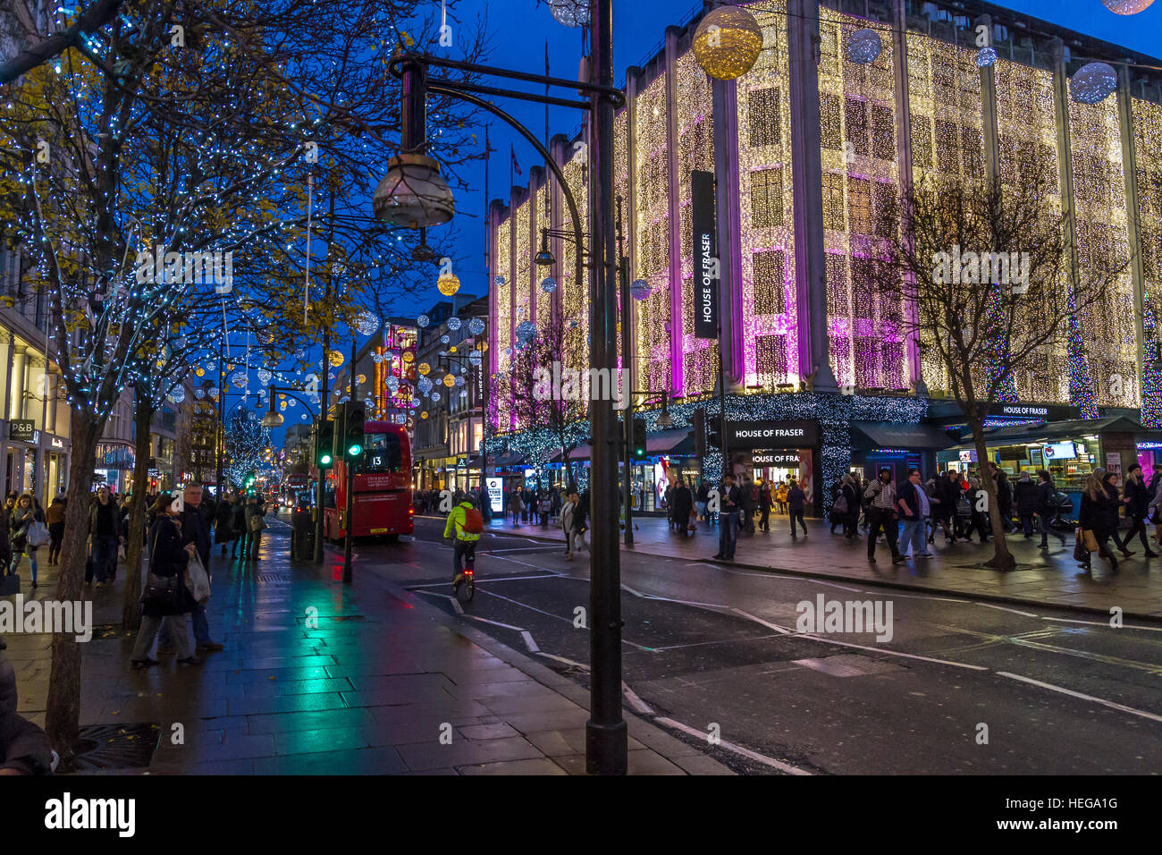 Christmas shoppers walking past The House Of Fraser on London's Oxford St at Christmas time covered in Christmas lights, Oxford St, London,UK Stock Photo