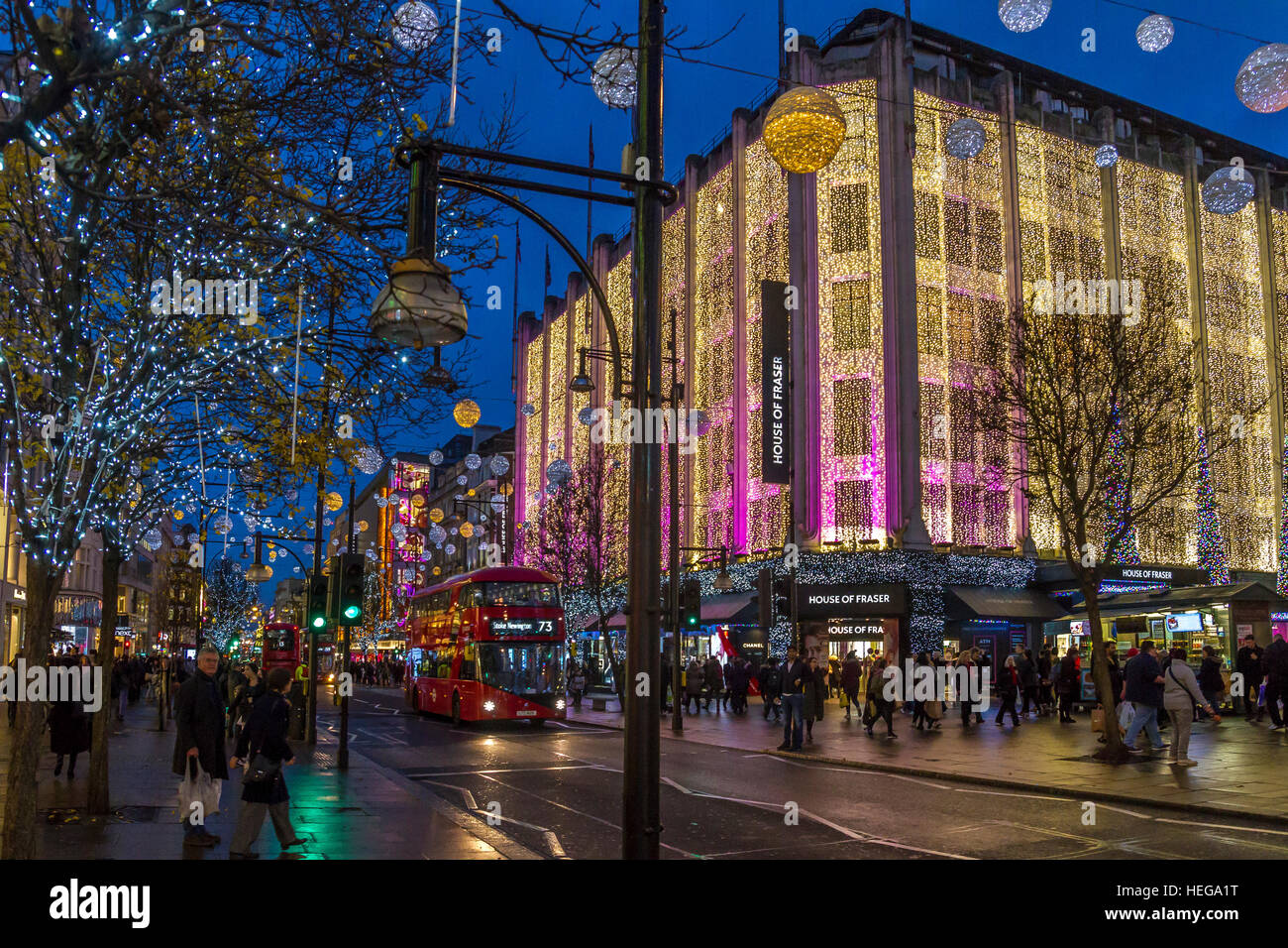 Christmas shoppers walking past The House Of Fraser on London's Oxford St at Christmas time covered in Christmas lights, Oxford St, London,UK Stock Photo