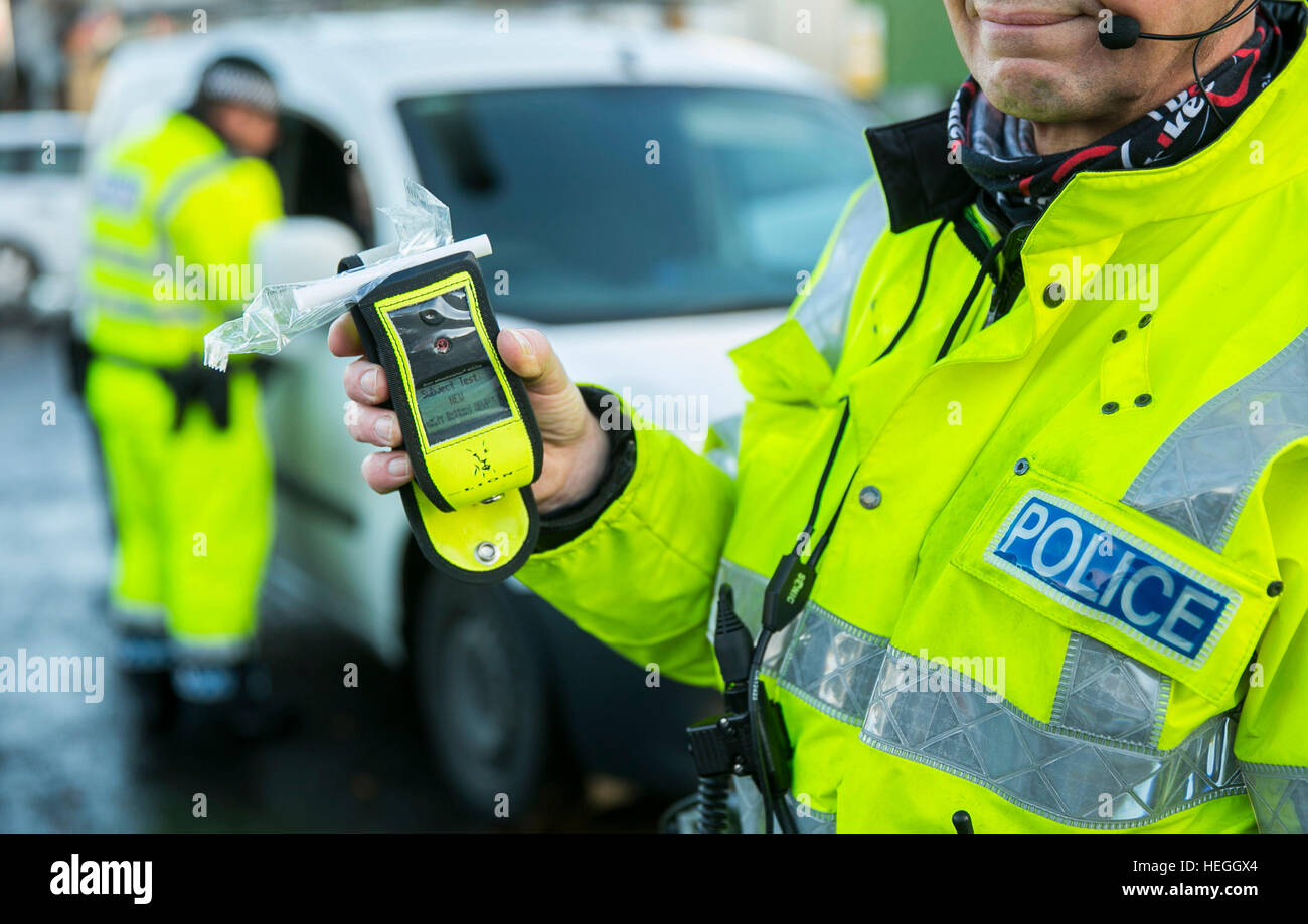 A PSNI Road Policing officer holds an operational breathalyser during a random drink driving checkpoint in Belfast. Stock Photo
