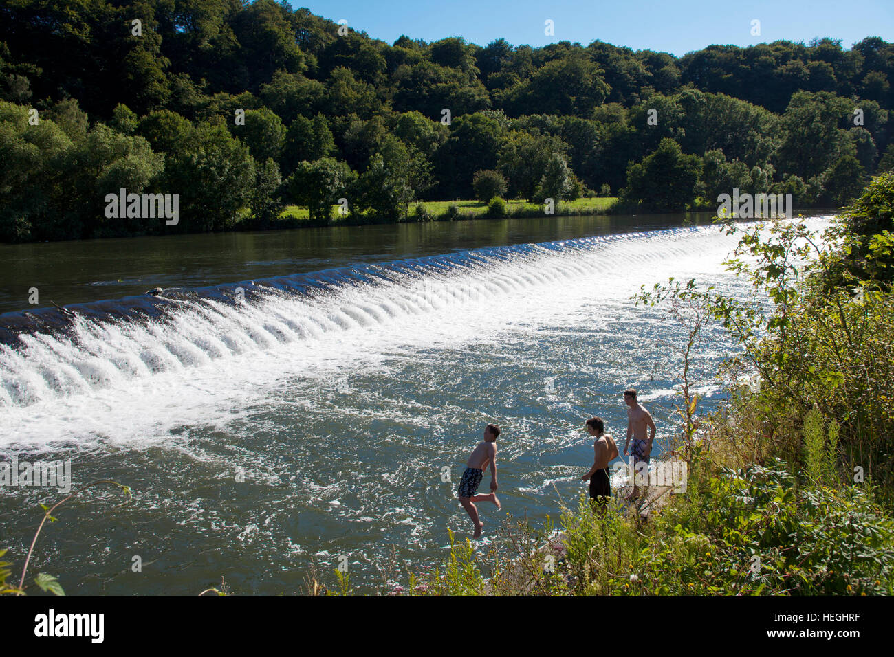 Germany, Witten, river Ruhr, boys jumping in the river at the spillway at the sluice in Herbede. Stock Photo