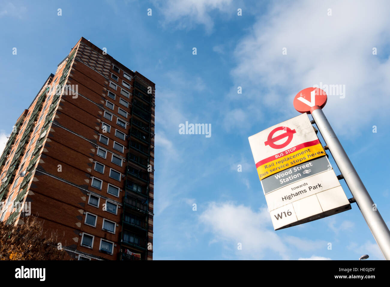 Bus Stop V at Wood Steet Station in Waltham Forest, East London, with rail replacement bus service sign, and tower block of flats or apartments. Stock Photo