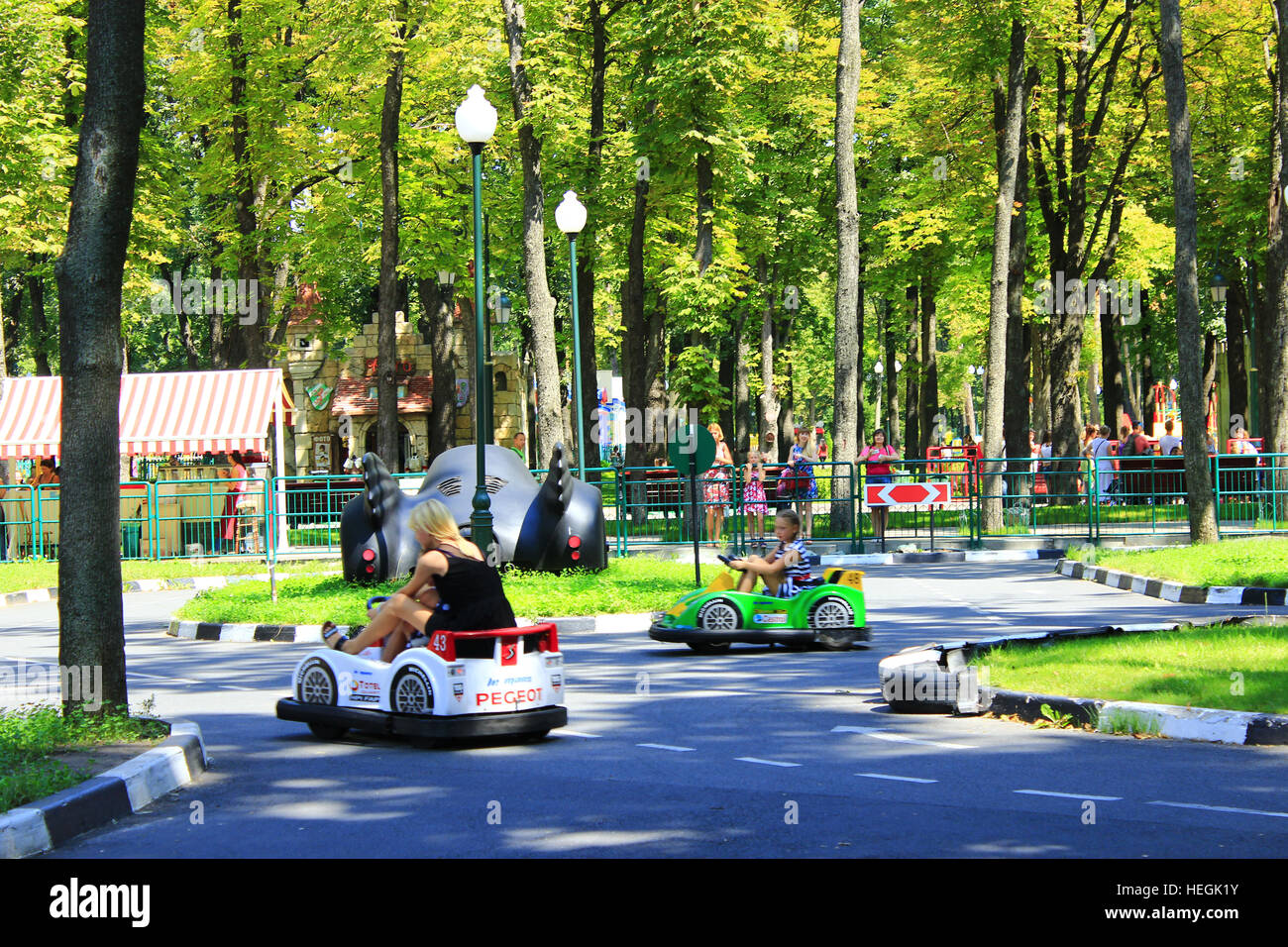 children with their parents drive the electric cars in Gorky park in Kharkiv Stock Photo